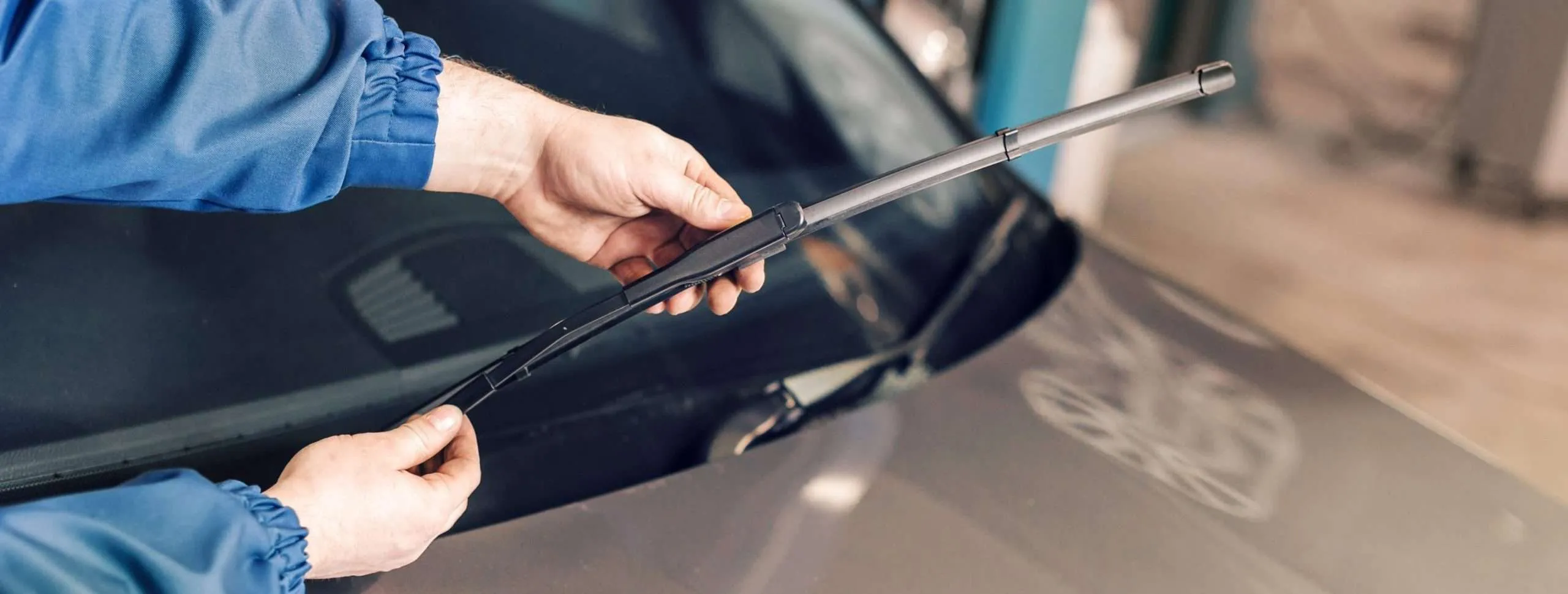Close-up of a technician's hands installing new windshield wipers as part of routine auto glass maintenance