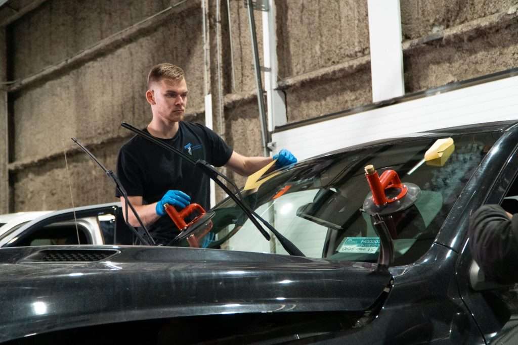Windshield Surgeons technician performing auto glass replacement services using suction grips