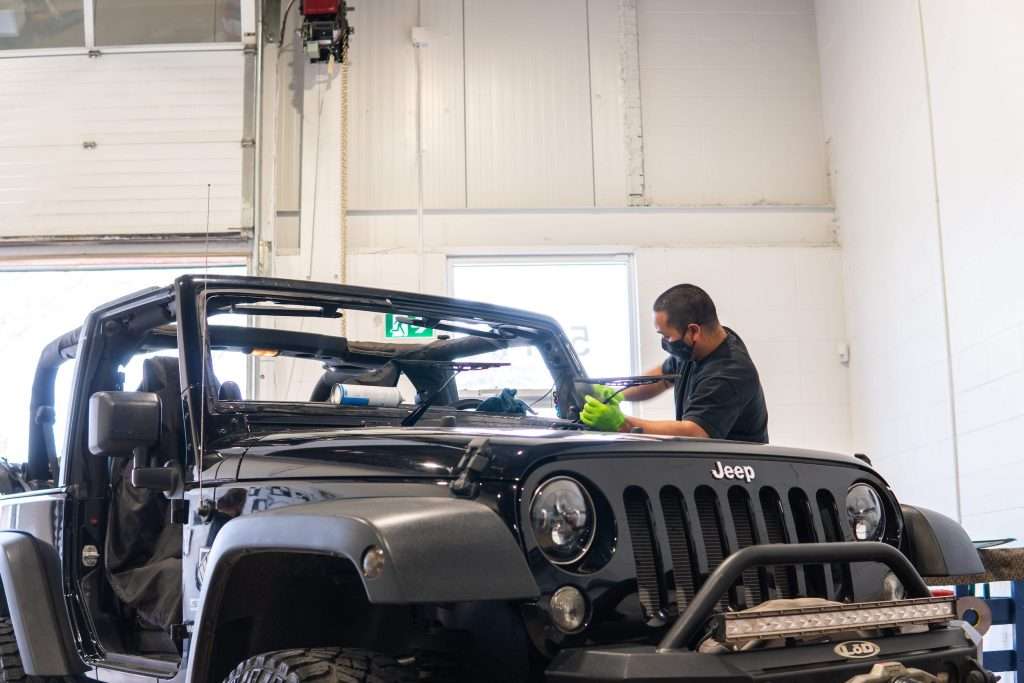 A Windshield Surgeons Technician preparing a Jeep Wrangler for a new replacement windshield