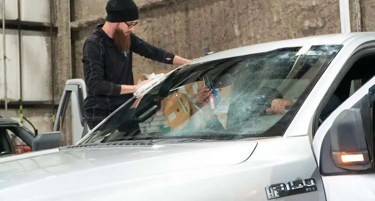 Technician in a Windshield Surgeons uniform cleaning a Ford F150 windshield