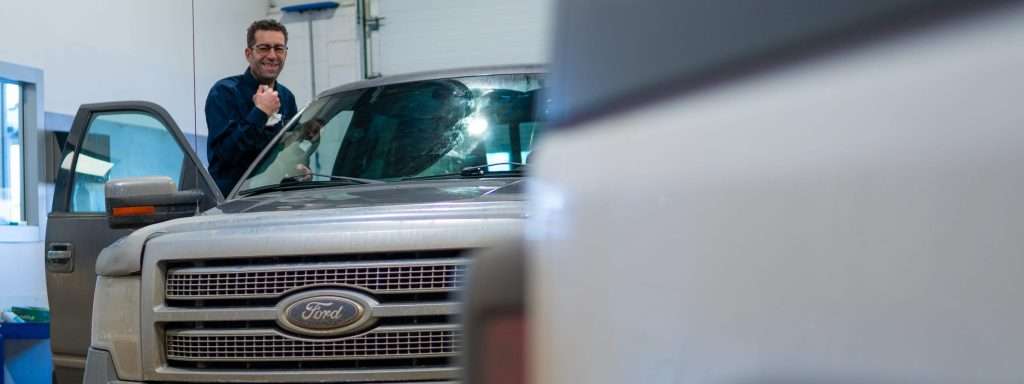 Windshield Surgeons Technician smiling while performing a Ford F150 windshield replacement