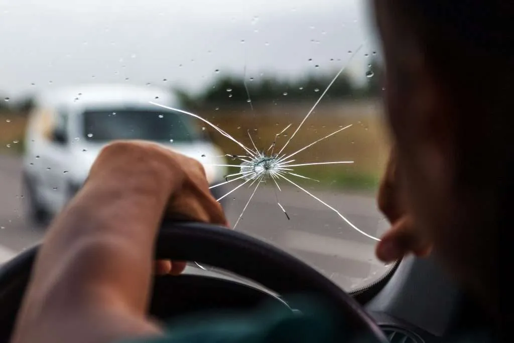 Driver’s view of a cracked windshield showing a significant rock chip needing immediate maintenance