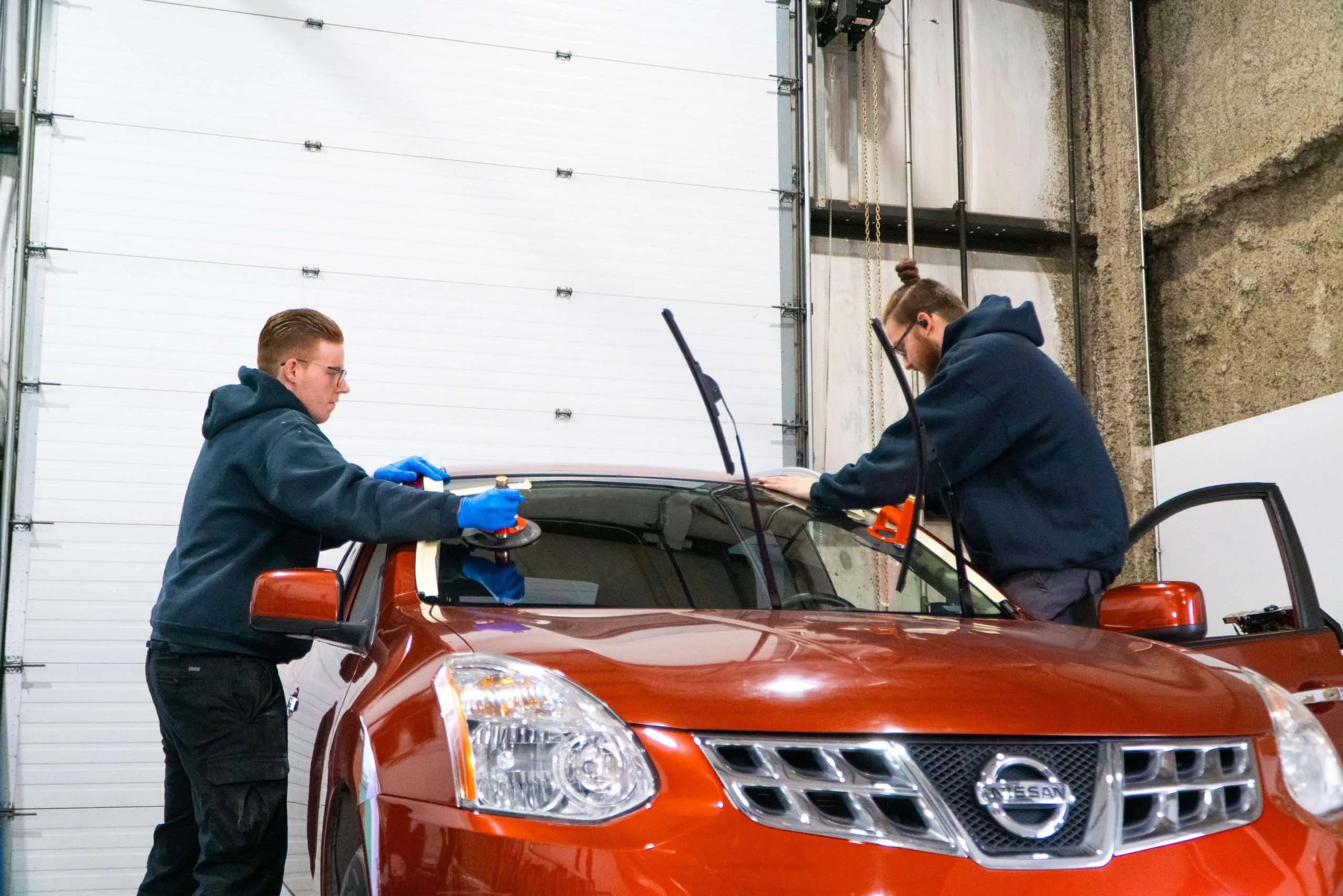Two Windshield Surgeons technicians performing a replacement after applying premium urethane adhesive.