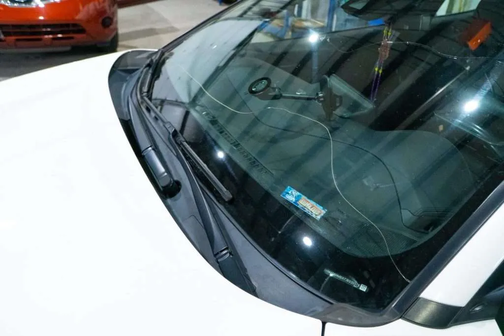 White vehicle with a long crack across the windshield parked inside a Windshield Surgeons auto glass shop in Edmonton
