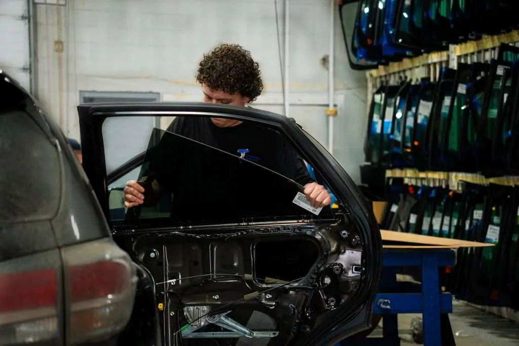 Windshield Surgeons technician installing a new window in a disassembled car door