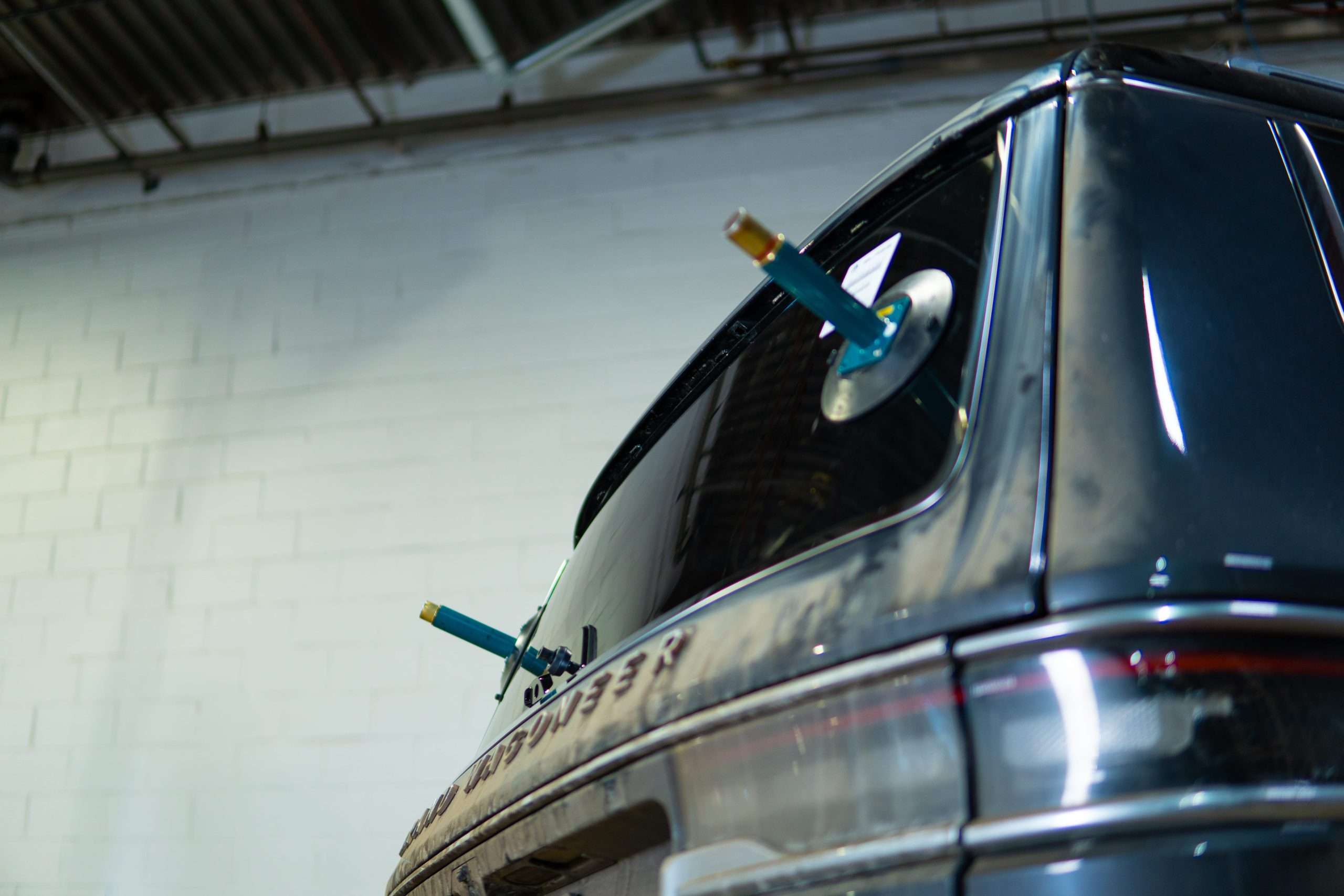 Close-up on rear door of an SUV with it's back glass about to be removed with suction tools