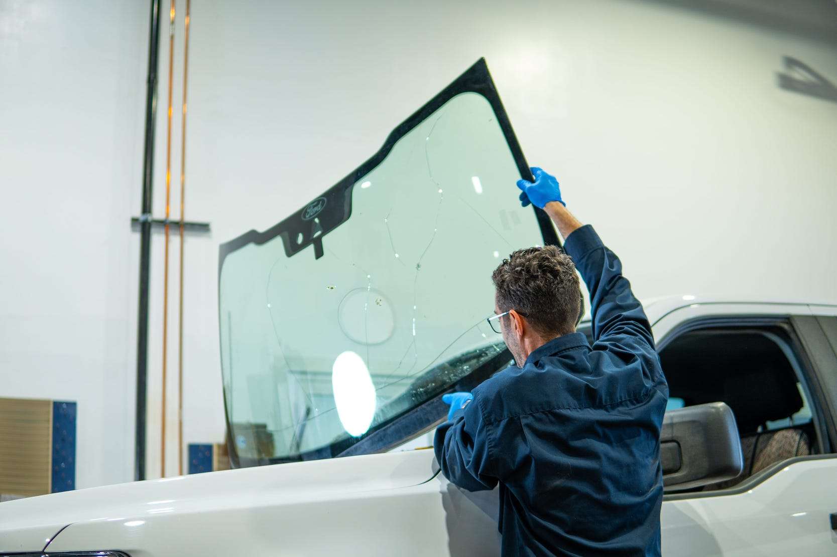 Windshield Surgeons technician removing a severely cracked windshield from a white Ford F150