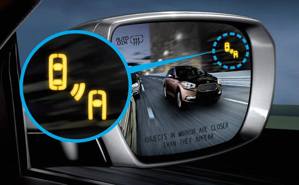 Close-up of a vehicle side mirror showing a Blind Spot Detection alert with a yellow warning symbol.