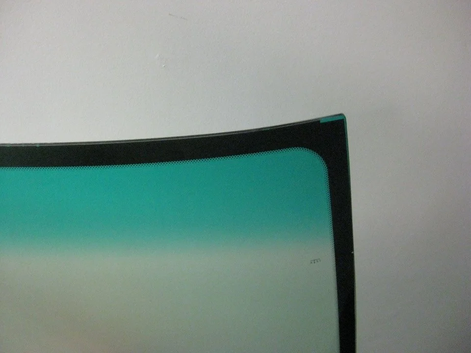 Close-up of a windshield corner showing a green-tinted shade band at the top.