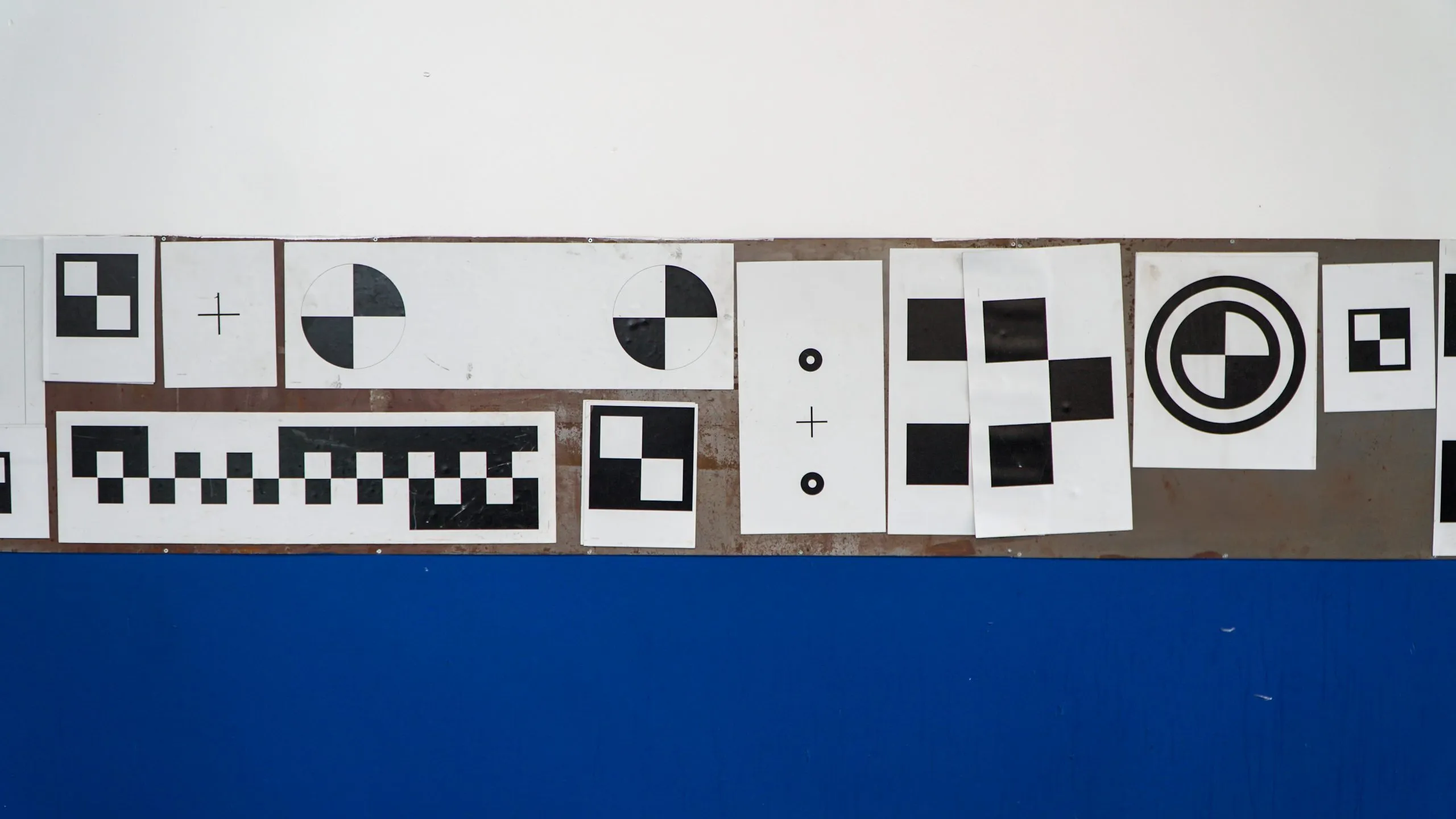 A line-up of ADAS calibration test pattern posters hung on a white and blue wall
